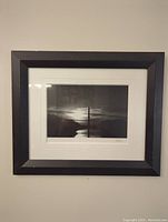Framed black and white photograph of the Washington Monument from a straight-on angle, showing the monument silhouette and reflective water with black frame and white matting.