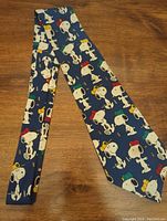 Full view of the vintage Snoopy necktie showing all-over Snoopy character prints on a dark blue background.