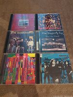 Photo showing all six CD cases with album covers by The Tragically Hip arranged in two rows of three, highlighting cover arts and general condition.