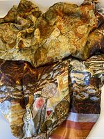 Silk chiffon fabric with abstract earth tone print and varied patterns, showing detailed folds and textures.
