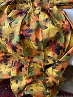 Close-up photo showing colorful floral and leaf pattern on cotton fabric, highlighting the tangerine, lemon, amber, green, and navy blue colors.
