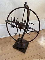 Full view of the metal sundial showing concentric circular rings and directional letters