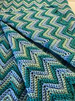 Close-up image showing chevron stitch pattern in turquoise, mint green, and sky blue yarn with textured ridged crochet work.