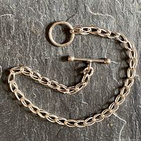 Full view of the linked sterling silver bracelet with toggle loop closure against dark background.