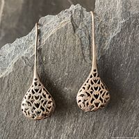 Pair of vintage sterling silver drop earrings shown full length on slate background, highlighting the long posts and bulbous dewdrop shaped filigree drops.