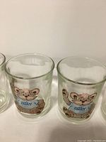 Front view of two Zeddy juice glasses showing the bear mascot with a blue shirt and the name 'Zeddy' on it.