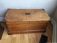 Closed chest top view showing pine wood surface, central metal plate and age wear
