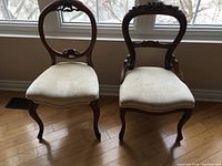 Front view of both chairs showing the differences in balloon back and cameo side chair styles and cream upholstery.