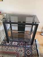 Clear front view of the metal frame and glass shelves on the side table on a patterned rug.