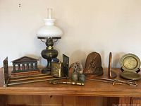 Full lot display of copper and brass decorative items on wooden surface including lamp, bookends, keys, and other small decor.