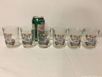 All six vintage Zeddy juice glasses in a row with a soda can for scale showing the size and condition of the glasses.