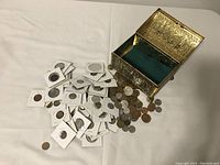 Chest open on table with pile of coins in flips and loose coins