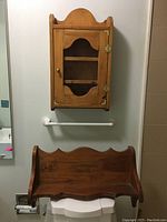 Wall cabinet hanging closed with clear view of front, showing door with cut-out window and brass knob, and the open shelf below it.