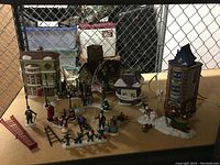 Full setup of Dickens Holiday Village houses and various holiday figurines on display surface.