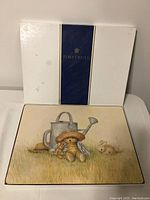 Photo of the original Pimpernel placemat box showing white exterior with blue and gold branding.