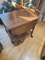 Wooden tea cart with two large spoked wheels and two caster wheels, top view showing wear and marks on wood surface