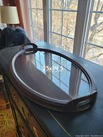 Oval wooden serving tray with clear glass top, positioned on a table near window. Measurements 25x14.5 inches visible in photo.