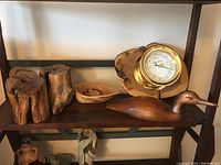 Photo showing all items on shelf including wood log pieces, bowl, duck decoy, and barometer on wood.