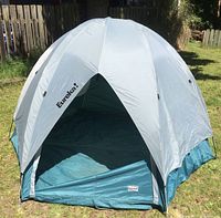 Front view of Eureka tent with entry open, showing white and teal fabric and dome shape