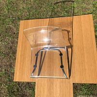 Top view of IKEA Tobias chair showing transparent acrylic seat and chromed steel legs placed on a wooden surface outdoors