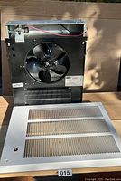 Front view of Dayton heater showing metal housing, large fan blade, metal heating element grill, and white front vent cover with missing screws and knob.