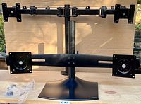 Photo of the Ergotron 33-322-200 dual monitor stand showing black metal frame, base, central pole and adjustable arms with VESA mounting plates.