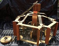 Side angle view of the teak and brass pendant light showing hexagonal shape, teak accents and brass framework with glass panels.