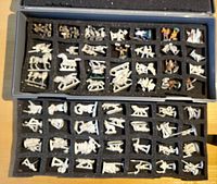 Two foam trays in plastic travel case holding approximately 60 pewter figures in individual compartments