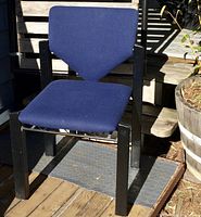 Side view of a vintage Lübke chair showing blue fabric upholstery on seat and back with chevron-shaped backrest and black wooden legs.