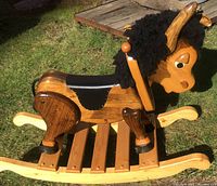 Side view of the whole rocking donkey showing smooth wood finish, rockers, saddle, and mane.