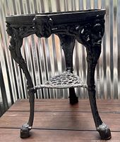 Heavy antique cast iron clawfoot table base with ornate legs and a central circular part showing detailed cast iron work