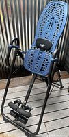 Full view of the Teeter 600ia inversion table showing blue perforated plastic backrest, padded lumbar support, and black metal frame.