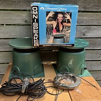 Three green omni-directional outdoor speakers, two without boxes and one in its original Paramount Pictures box, with cables and wire shown.