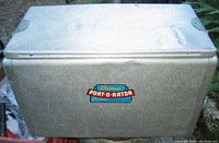 Front and top view of the silver textured aluminum cooler featuring the Cronco Port-O-Rator label with minor dents visible.