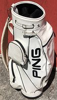 Front view of vintage PING white golf bag with black PING logo and front pockets