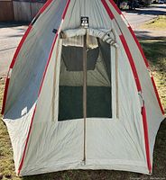 Front view of vintage King-Seely Thermos pop-up tent showing zippered entrance with mesh window and red trim along the canvas edges.