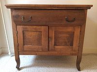 Front view of the wooden cabinet showing drawer and double doors with metal handles and knob