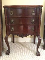 Front view of wooden side table showing three drawers with metal ring pull handles and carved legs.