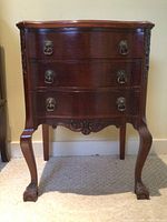Full frontal view of the wooden side table showing three drawers and claw foot legs.