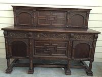 Full front view of the large wooden sideboard showing carved decorative panels and legs