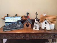 Photo showing the full collection including bird houses, wooden ducks, and the painted mailbox arranged on a wooden surface.