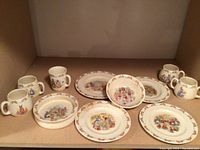 Overview of 4 plates, 2 bowls, 4 mugs arranged together showing Bunnykins designs and wear