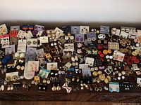 Top down view of the entire collection of costume jewelry earrings spread out on a wooden surface.