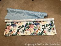 Two fabric bolts displayed side by side; one with floral print, one solid light blue.