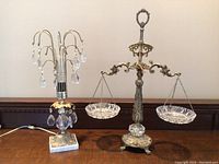 Photo showing both the lamp with hanging crystal drops and the ornate vintage weigh scale side by side on a wooden surface.