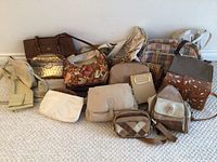 Photo showing entire lot of 12 assorted purses and handbags arranged on the floor, displaying various styles, colors, and materials