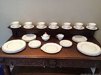 Full set of Royal Doulton Richelieu china displayed on wooden dresser, showing cups, saucers, plates, sugar bowl, and creamer.