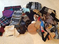 Overview photo showing a variety of scarves, handkerchiefs, gloves, and hats arranged on the floor.