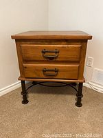 Front view of pine wood side table with two drawers and black metal legs.