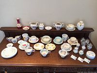 Wide shot of all porcelain items on wooden table and back ledge